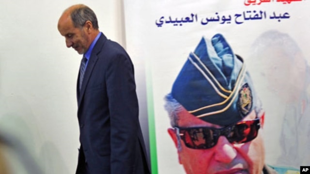 Mustafa Abdel Jalil, chairman of the Libyan National Transitional Council walks in front of a poster of slain Libyan rebels military commander General Abdel Fattah Younes after speaking at a news conference in Benghazi, Libya, August 9, 2011