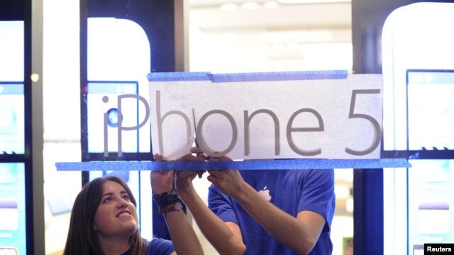 Empleados de Apple cuelgan un cartel promocional del iPhone 5 en uno de puntos de venta de la compañía, poco antes de que las ventas comenzaron en San Francisco, California.