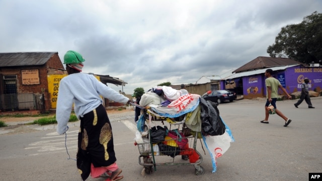 A woman collecting plastic bags carries her cart through the streets of Johannesburg's Alexandra township, December 12, 2012.