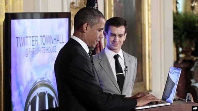 President Barack Obama types during his live-tweet as Twitter co-founder and Executive Chairman Jack Dorsey looks on during the first-ever Twitter Town Hall,  July 6, 2011, in the East Room of the White House