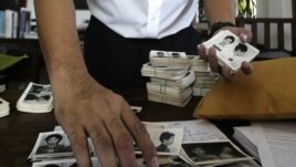 In this photo taken on Aug. 20, 2012, Director of Documentation Center of Cambodia, Chhang Youk arranges photos, a part of about a thousand of newly-discovered photo collection of detainees at the former Khmer Rouge main prison S-21, in his office in Phno
