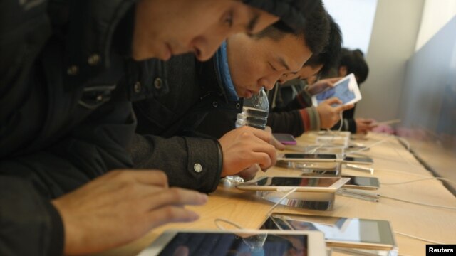 Customers test out Apple iPads in an Apple Store in downtown Shanghai, February 29, 2012.