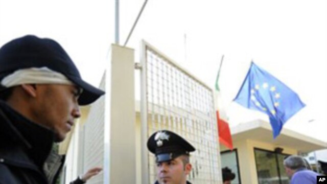 A would-be immigrant is escorted to register at a re-opened detention center on the island of Lampedusa, Italy, Sunday, Feb. 13, 2011.