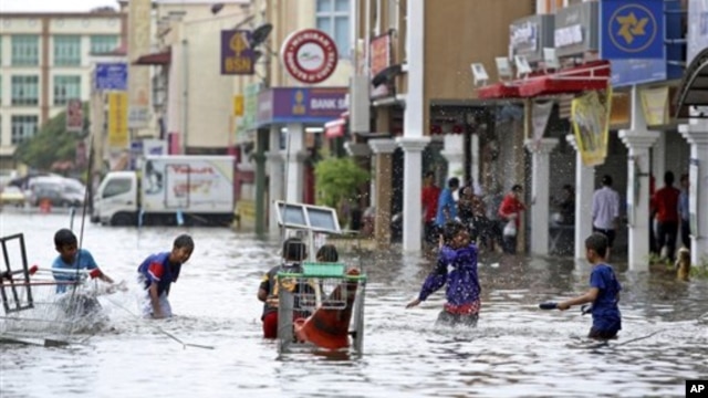 Trẻ em chơi đùa trong một con đường bị ngập nước sau các cơn mưa lớn, ở Kota Bharu, Malaysia 25/12/12