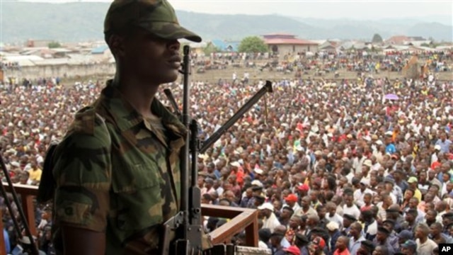 A soldier from the M23 rebel group looks on as thousands of Congolese people listen during an M23 rally, in Goma, eastern Congo, Nov. 21, 2012