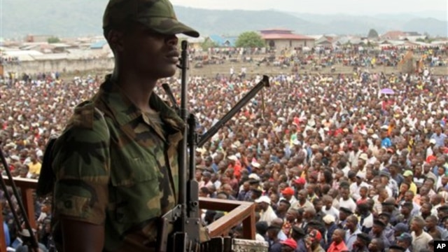 A soldier from the M23 rebel group looks on as thousands of Congolese people listen during an M23 rally, in Goma, eastern Congo, Nov. 21, 2012