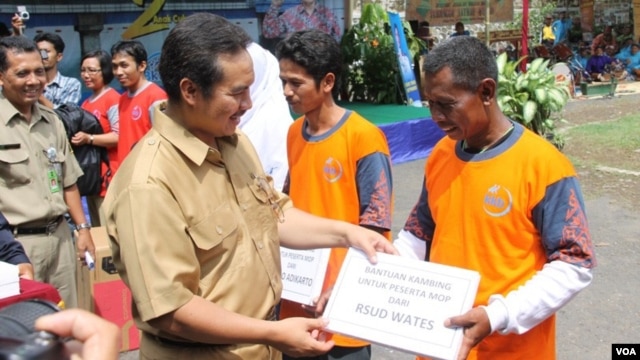 Petugas pemerintah kabupaten Kulonprogo, DI Yogyakarta, memberikan hadiah simbolis yang menyatakan hadiah kambing bagi mereka yang melakukan vasektomi. (VOA/Nurhadi Sucahyo)
