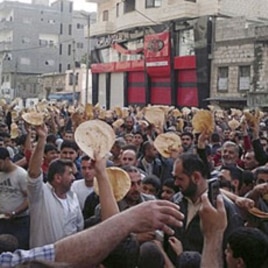 In this citizen journalism image made on a mobile phone and acquired by AP, May 3, 2011, Syrian men carry pieces of bread during a protest against Syrian President Bashar Assad's regime, in the coastal town of Banias