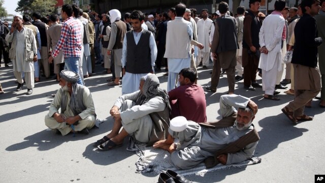 Afghan protesters sit on the ground to block one of the main Kabul streets during a demonstration against the government, in Kabul, Afghanistan, Oct. 7, 2015. 
