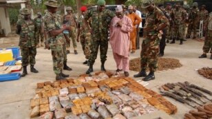 Military officials stand near ammunitions seized from suspected members of Hezbollah after a raid of a building in Kano, Nigeria, May 30, 2013.