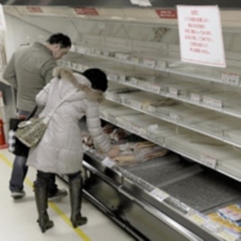 People shop for food from an almost empty shelf at a Tokyo store, March 15, 2011.