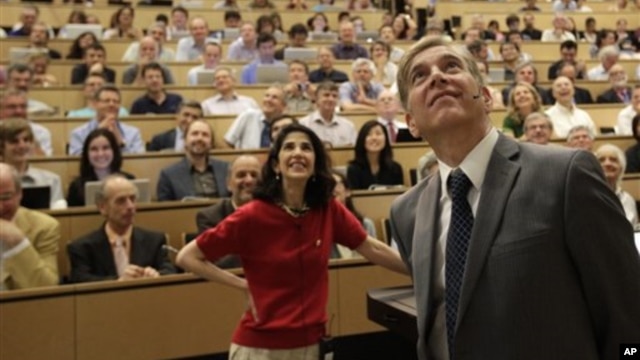 Fabiola Gianotti, Atlas team spokeswoman, and Joe Incandela, from the CMS team, look at a screen Wednesday during a scientific seminar to deliver the latest update in the search for the Higgs boson