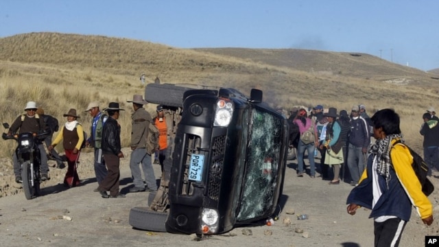 People surround an overturned car during a protest at the Tinaya copper mine owned by Swiss-based Xstrata plc in Espinar, Peru, May 28, 2012. 