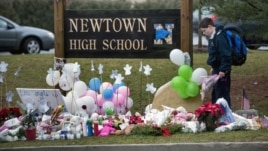 A student looks for a place to leave flowers at a makeshift memorial for the victims of the Sandy Hook Elementary School shooting at the entrance of Newtown High School December 18, 2012 in Newtown, Connecticut.