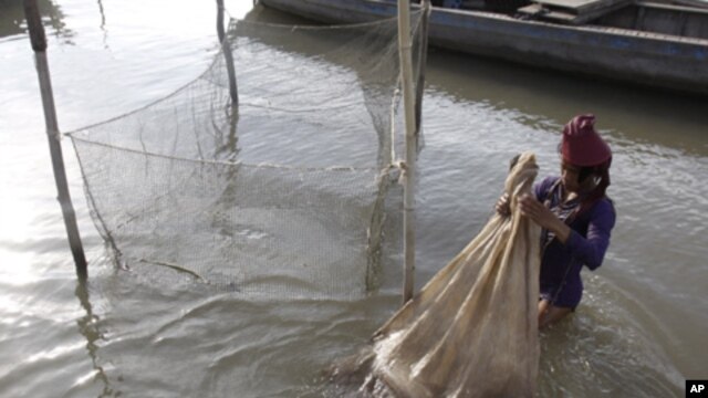 A Cambodian fisherman holds a bag loaded with fish he caught in the Mekong River near Phnom Penh, Cambodia, Tuesday, April 19, 2011.