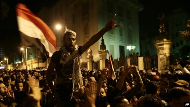 Egyptian protesters chant anti-Muslim Brotherhood and Egyptian President Mohammed Morsi slogans outside the presidential palace after they broke a barbed wire barricade keeping them from getting closer to the presidential palace, in Cairo, Dec. 7, 2012.