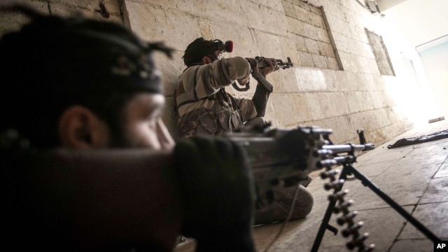 Free Syrian Army fighters aim their weapons at the entrance of a building during heavy clashes with government forces in Aleppo, Syria, December 5, 2012.