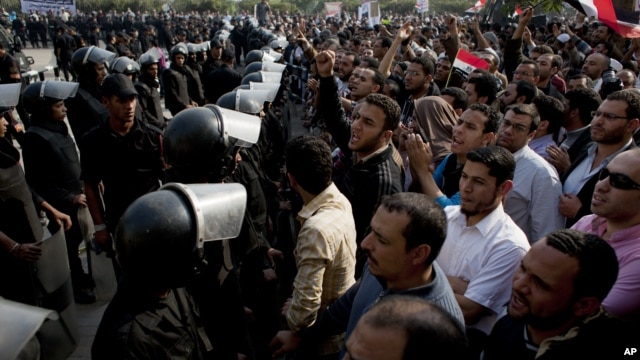 Supporters of Egyptian President Mohammed Morsi chant slogans as riot police, left, stand guard in front of the entrance of Egypt’s top court, in Cairo, Egypt, Sunday, Dec. 2, 2012.