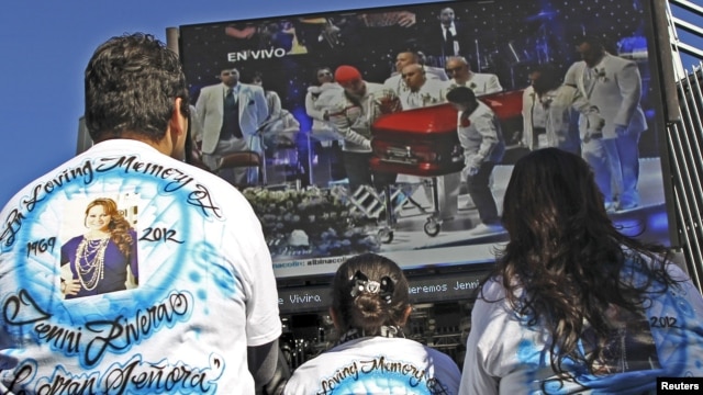Admiradores de La Diva de la Banda observan en una pantalla los funerales de la cantante.