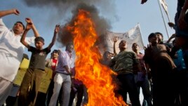 Pakistani Christians chant slogans after they burn a tire during a demonstration demanding that the government rebuild their homes after they were burned down following an alleged blasphemy incident, in Islamabad, Pakistan, March 10, 2013.