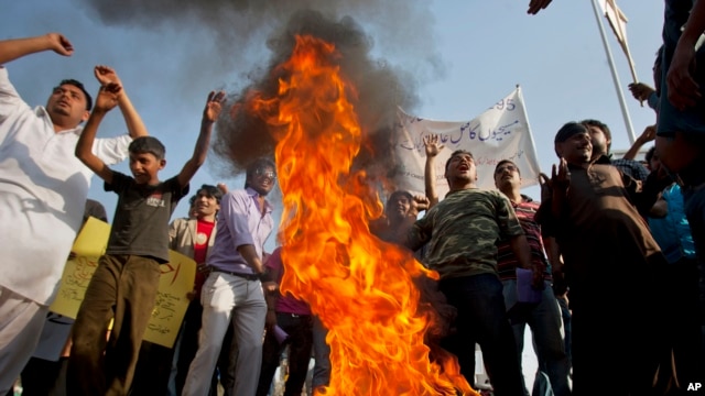 Pakistani Christians chant slogans after they burn a tire during a demonstration demanding that the government rebuild their homes after they were burned down following an alleged blasphemy incident, in Islamabad, Pakistan, March 10, 2013.