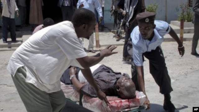 Somalis carry a wounded man away on a stretcher after the blast at the Somali National Theater in Mogadishu, Somalia, April 4, 2012.