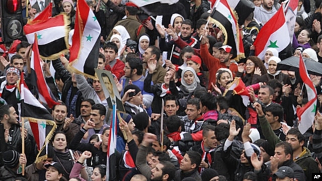Syrians wave national flags as they rally in central Damascus in support of President Bashar al-Assad's, Nov. 16, 2011.