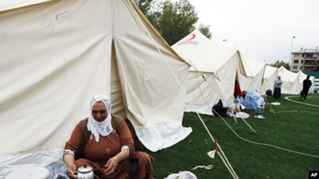 An earthquake survivor washes dishes outside her tent in a tent city set up in a soccer field in Ercis, Van, Turkey, October 27, 2011.