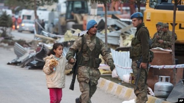 A soldier helps a girl to cross a street after an earthquake in Ercis, Turkey October 24, 2011.