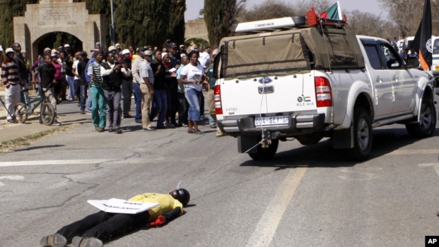 An effigy of the killer of right wing leader Eugene TerreBlanche is dragged behind a vehicle past protesters outside the court in Ventersdorp, South Africa, August 22, 2012. 