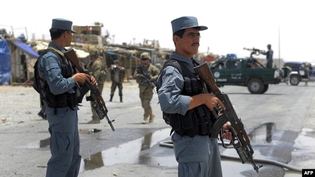 Afghan policemen stand guard as two US soldiers (C) arrive at the site of a twin suicide attack near NATO's Kandahar Air Base, June 6, 2012.