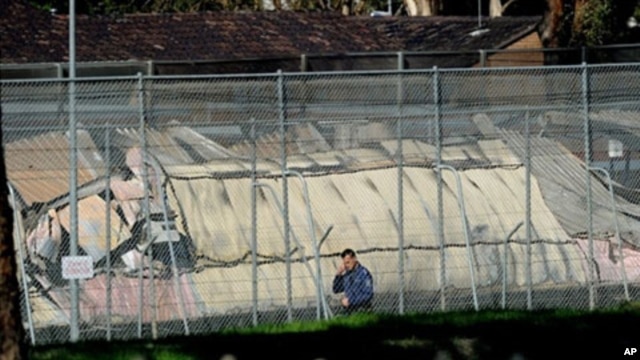 A man walks past the smoldering remains of burnt out buildings at Sydney's Villawood Detention Centre, April 21, 2011