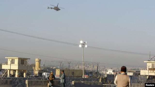 Afghan security forces keep watch as a NATO helicopter flies over at the site of an attack in Jalalabad December 2, 2012. Suicide attackers detonated bombs and fired rockets outside a major U.S. base in Afghanistan on Sunday, killing five people in a braz