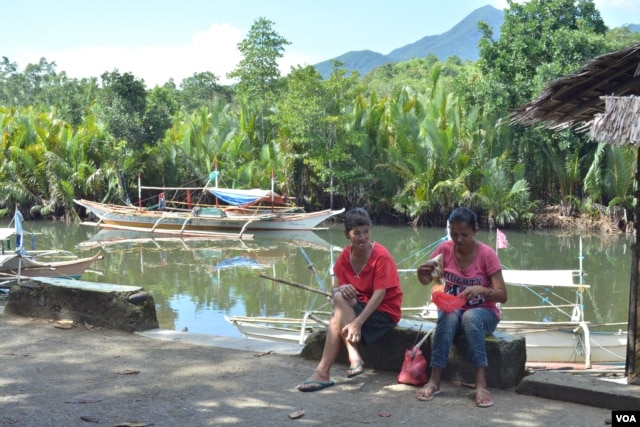 A woman and her neighbor chat while she sorts fish in this small fishing town along Ulugan Bay, which fronts the South China Sea, in Bahile, Palawan province, Philippines. (Photo: Simone Orendain for VOA)