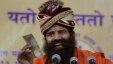 FILE - Indian yoga guru Baba Ramdev displays an Indian banknote as he makes fun of people running after money while addressing supporters in Ahmadabad, India.