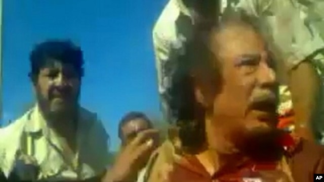 Image taken from amateur video posted on a social media website and obtained by Reuters, October 21, 2011, shows former Libyan leader Moammar Gadhafi, covered in blood, after his capture by NTC fighters in Sirte.