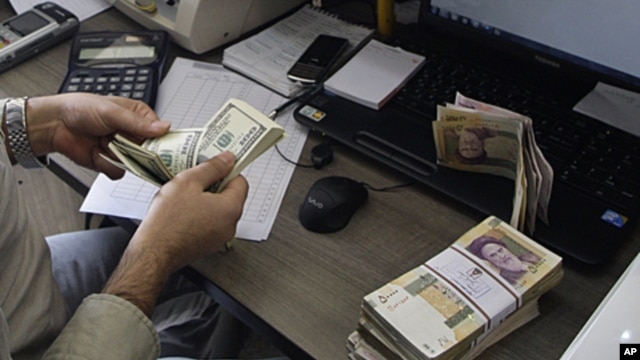 A currency exchange bureau worker counts US dollars, as Iranian bank notes are seen at right with portrait of late revolutionary founder Ayatollah Khomeini, in downtown Tehran,  December 21, 2011. 