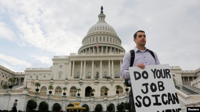 Một công chức chính phủ liên bang, đứng trên thềm trụ sở Quốc hội, cầm tấm bảng với dòng chữ "Xin hãy thực hiện phần việc của quý vị để tôi có thể làm công việc của tôi" 