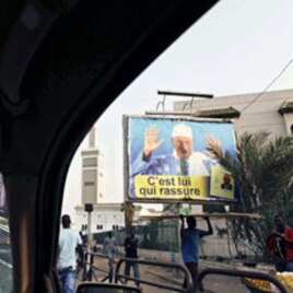 A defaced poster of Senegal's President Abdoulaye Wade (R) with paint splattered on it, is seen through the window of a taxi driving through the center of Dakar, March 1, 2012