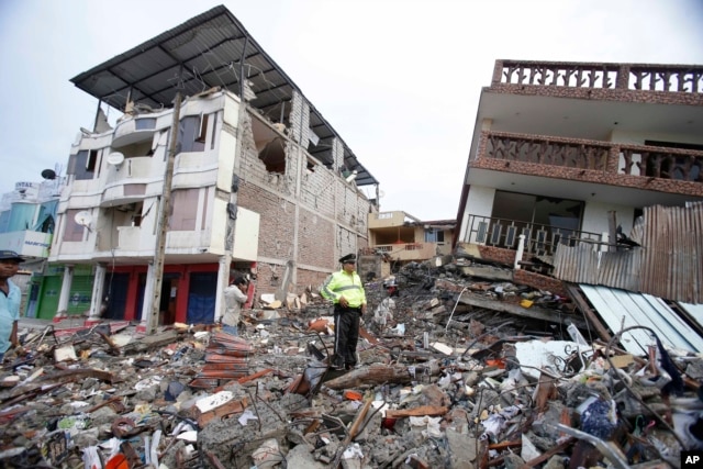 Cảnh sát đứng trên đống đổ nát bên cạnh những tòa nhà bị phá hủy vì trận động đất ở thành phố Pedernales, Ecuador, ngày 17 tháng 4, 2016.