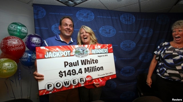 Paul White, from Ham Lake, Minnesota, stands with his partner Kim VanReese as he holds a check for his $149.4 million portion of a $448.4 million Powerball jackpot prize.