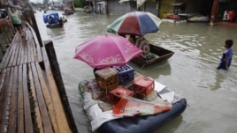 Residents use makeshift floats as others cross a makeshift bridge built over a flooded road in suburban Pasig, east of Manila, Philippines, August 15, 2012.