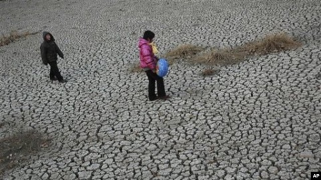 People walk on a dried up pond at Hanzhuang village in Tangyin county in central China's Henan province (File Photo)