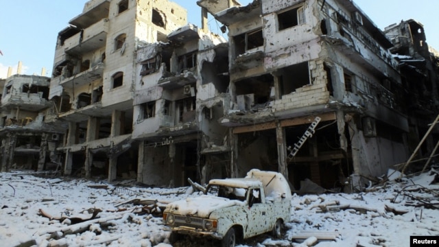 Sebuah mobil yang rusak dan bangunan yang tertutup salju terlihat di daerah Jouret al Shayah, Homs, Suriah, 10 Januari 2013. (Foto: dok). Para aktivis melaporkan pasukan yang setia kepada Presiden Assad telah menewaskan lebih dari 100 orang di Homs, Suriah Tengah.