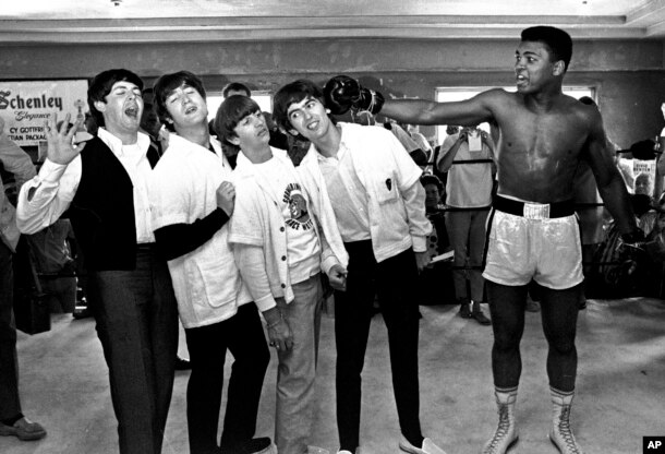 FILE - The Beatles, from left, Paul McCartney, John Lennon, Ringo Starr and George Harrison take a fake blow from Cassius Clay, who later changed his name to Muhammad Ali, while visiting the heavyweight contender in Miami Beach, Fla., Feb. 18, 1964.