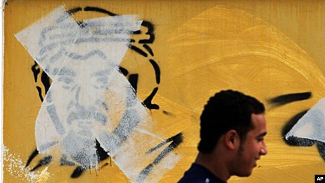 A Bahraini man  in Manama passes by an image of Shiite leader Hassan Meshaima, crossed out with a paint roller by authorities, February 24, 2011