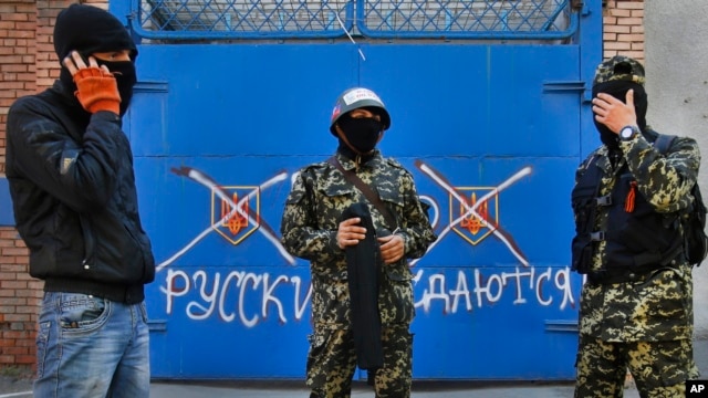 Dân quân thân Nga đứng trước một cánh cổng với hàng chữ 'Nga không đầu hàng' tại Slovyansk, miền đông Ukraine, ngày 25/4/2014.