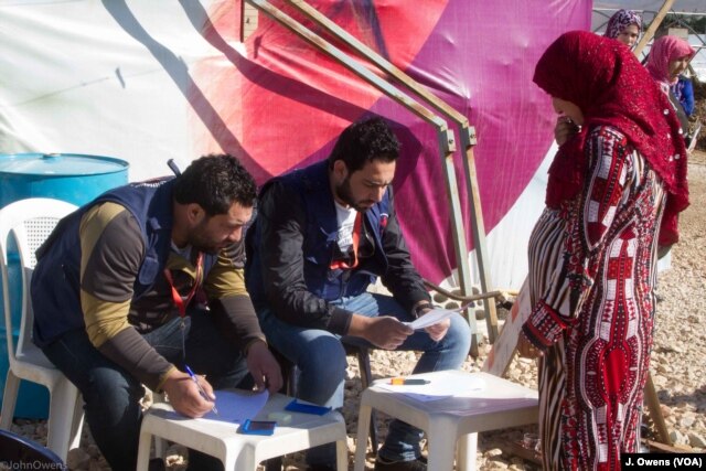 A Syrian women registers her details ahead of collecting items provided to help protect the refugees' makeshift shelters against the elements this winter.