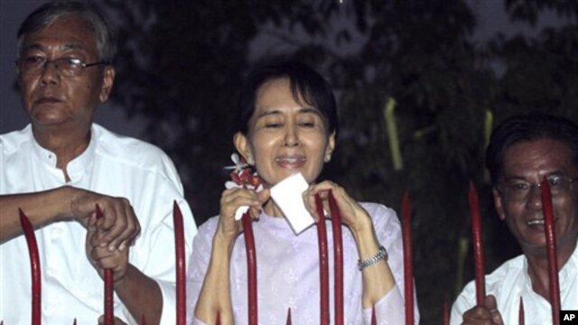 Burma's pro-democracy leader Aung San Suu Kyi, flanked by her party officials, talks to the supporters at the gate of her home in Rangoon, 13 Nov 2010