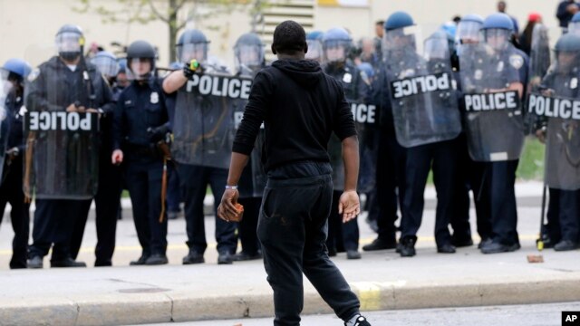 Người biểu tình cầm gạch đá đi ngang qua cảnh sát tại thành phố Baltimore, ngày 27/4/2015.
